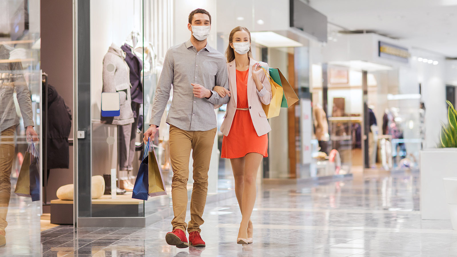 young couple wearing medical mask with shopping bags walking in mall
